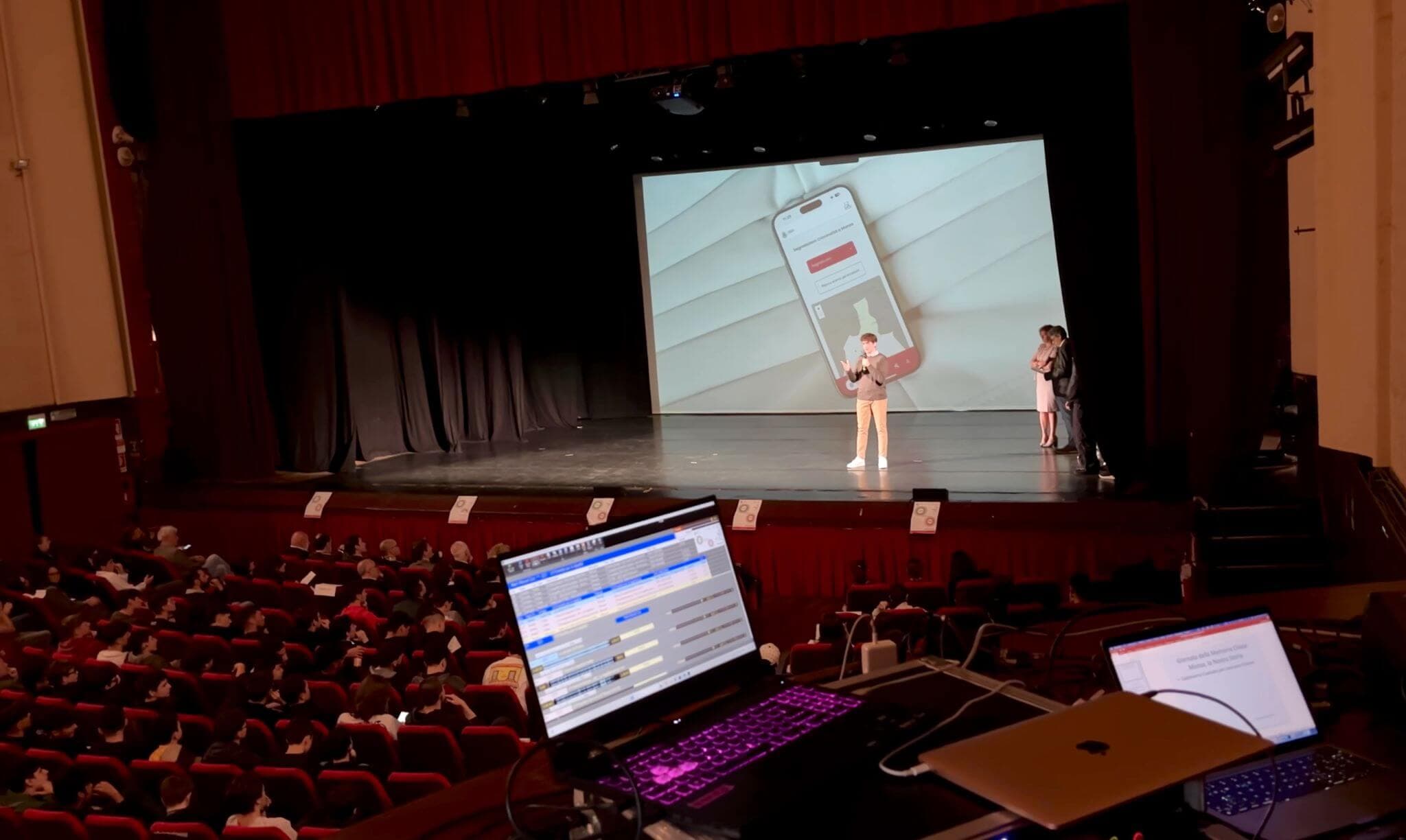 Vista del teatro durante il talk TEDx, con un mockup app proiettato sullo schermo